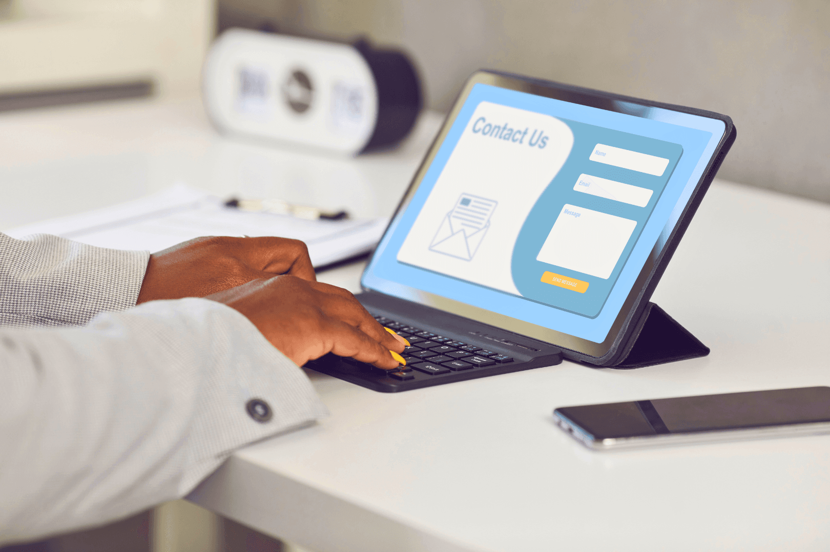Person using a tablet to fill out an online contact form at a desk.