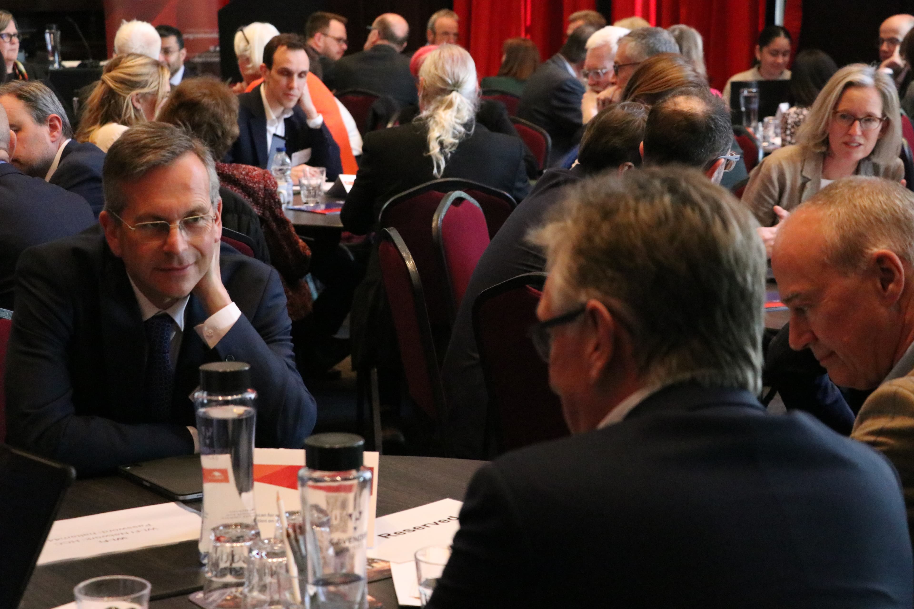 NHS trust leaders in discussion around tables at a forum event.