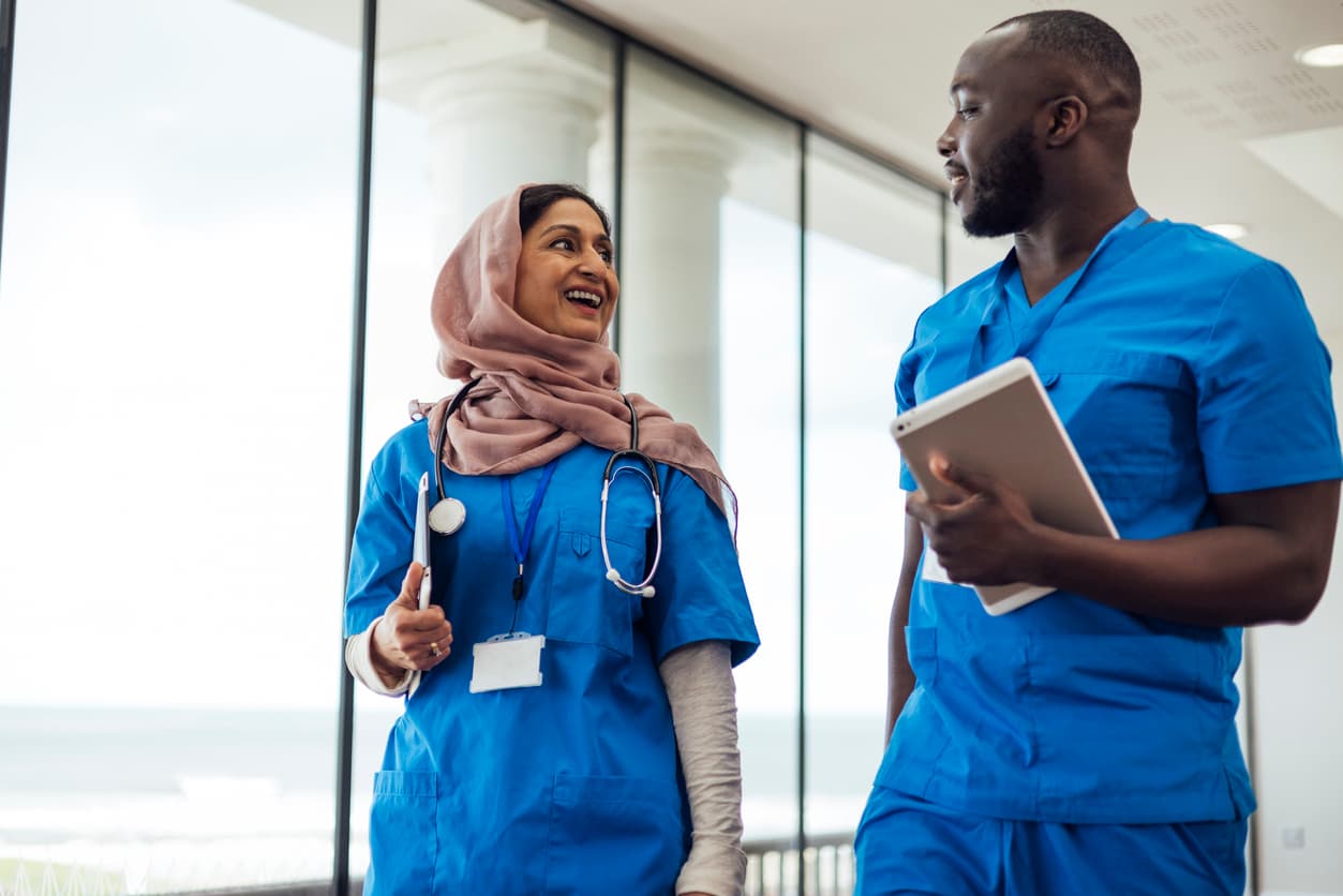 Two healthcare professionals walking down corridor in conversation